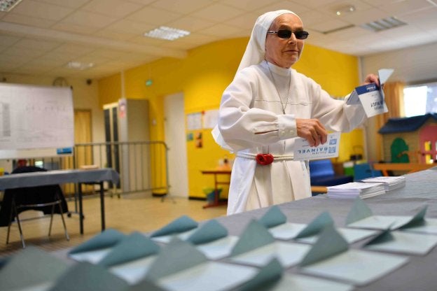 Una monja elige entre las papeletas antes de votar en un colegio de Nantes. :: LOIC VENANCE / afp
/
