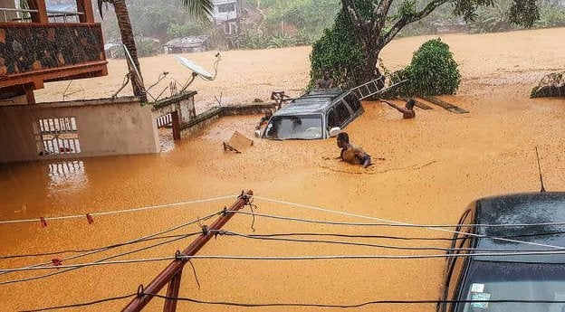 Dos hombres intentan avanzar en medio de la inundación. :: afp