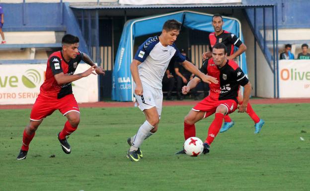 Corpas, entre dos jugadores del Mérida.