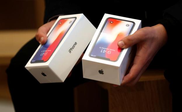 Un hombre sostiene dos cajas con el nuevo iPhone X./Reuters