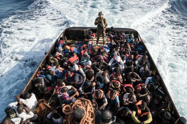 Un guardia costero sube a una embarcación que trasladaba a 150 inmigrantes desde Libia. :: afp
/