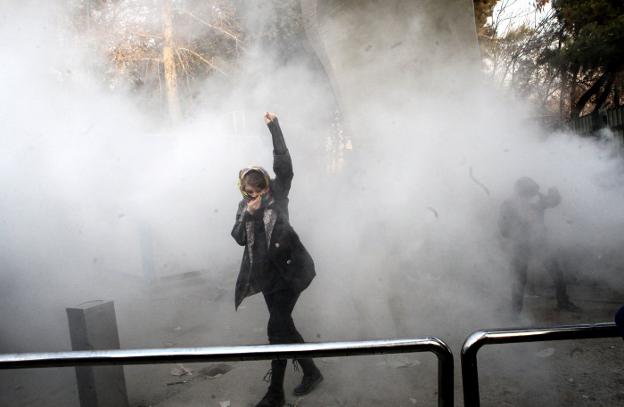 Una estudiante avanza entre gases lacrimógenos en las protestas contra el Gobierno en la Universidad de Teherán. :: efe/