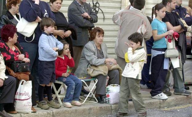 Gente sentada en sillas domésticas en calle Carretería, al paso de la procesión (archivo)./SUR