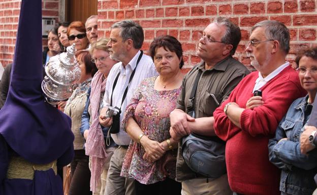 Turistas contemplan, impresionados, una procesión de Semana Santa en el centro de Málaga (archivo)./SUR