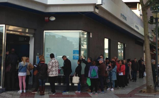 Numerosas personas hacen cola a las puertas de una de las sucursales de Endesa en Málaga./SUR