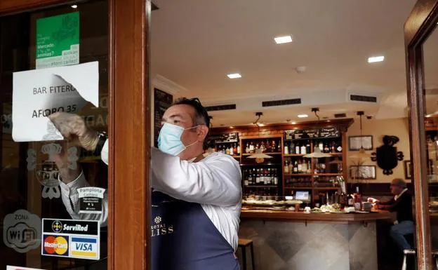 A waiter removes a poster with capacity limitations in Pamplona./EFE