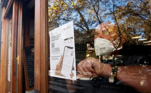 A waiter places a poster asking for proof of vaccination in a Barcelona restaurant./EFE