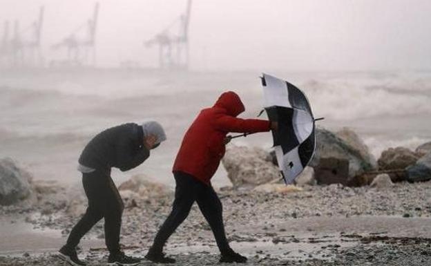 File photograph of people battling the weather along a shoreline. 
