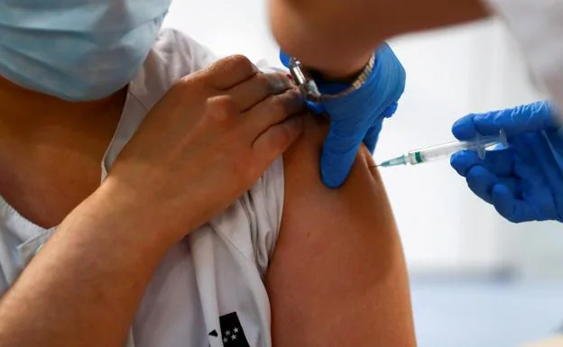 A health worker receives a dose of a coronavirus vaccine.