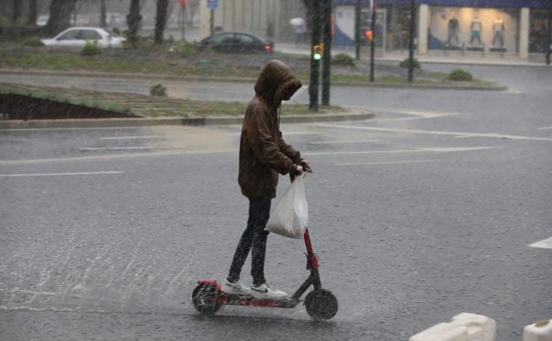 A young man on a scooter during a storm in Málaga. /SALVADOR SALAS