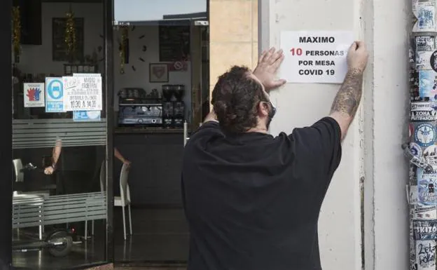 A waiter puts up a reduced capacity sign at a hospitality business in Pamplona.