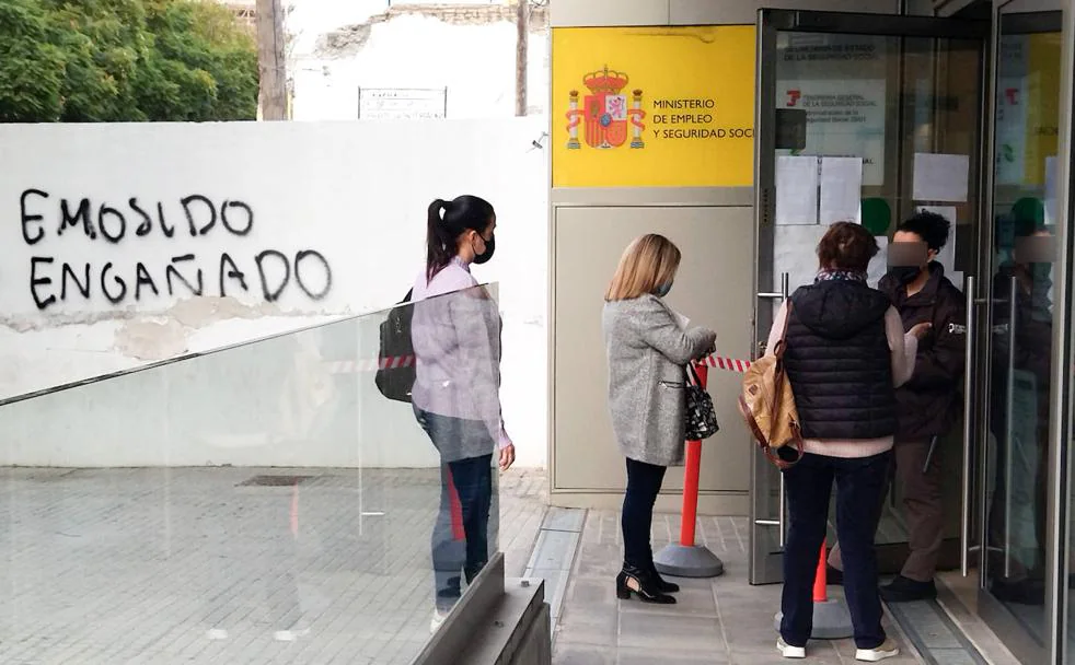 A group of people wait outside a Social Security office in Malaga. 