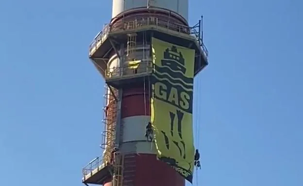 Greenpeace protesters hang a banner from a chimney