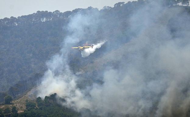 Aircraft drop water on the major forest fire still burning in Malaga province