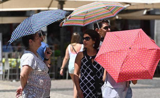 People walk under the shade of an umbrella through the centre of Madrid./EFE