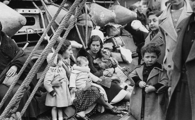 A group of women and children wait to be transported to France. 