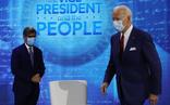 Joe Biden se acerca a su silla ante la mirada del moderador del programa en Filadelfia./AFP