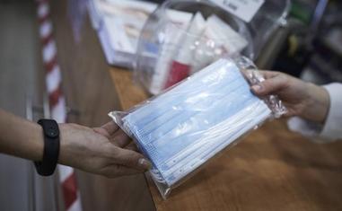 Una farmacéutica dispensa una mascarilla quirúrgica./Efe