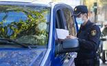 Un policía comprueba la autorización de un conductor para poder circular durante la pandemia/