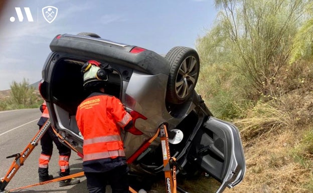 Bomberos rescatan a los dos ocupantes de un vehículo volcado en La Viñuela