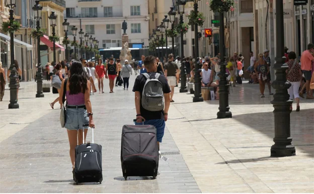 Los turistas se mueven con sus maletas por la calle principal del centro histórico de Málaga. 