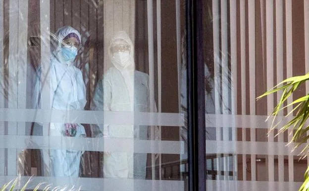 Dos trabajadores con trajes protectores contra materiales peligrosos en la residencia de mayores de Cádiz en medio de una pandemia.  /EFE